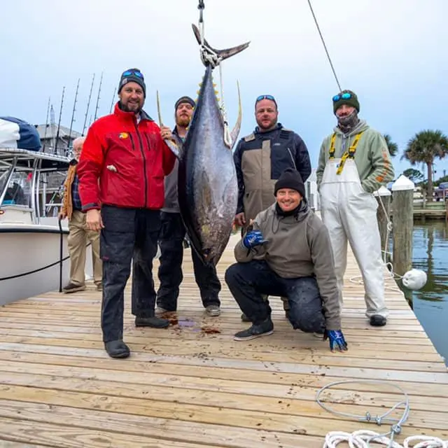 a man holding a fish near a boat posing for the camera